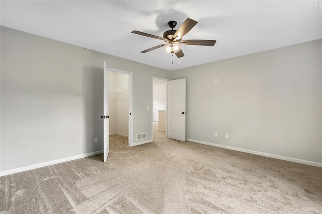 unfurnished bedroom featuring carpet floors, baseboards, a walk in closet, and visible vents