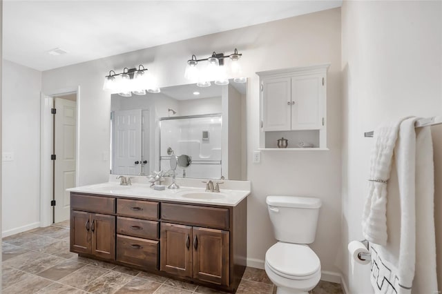 bathroom featuring double vanity, a sink, toilet, and a shower stall