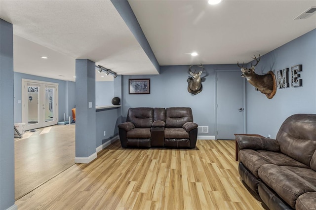 living area featuring baseboards, visible vents, and light wood-type flooring