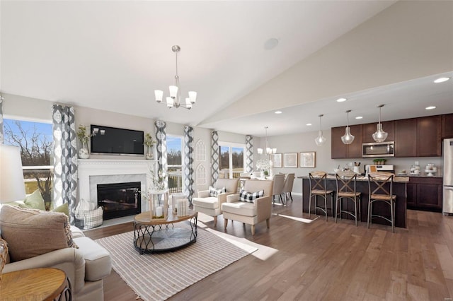 living area featuring a wealth of natural light, a notable chandelier, a premium fireplace, and wood finished floors