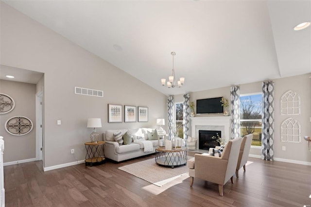 living room featuring visible vents, an inviting chandelier, a premium fireplace, and wood finished floors