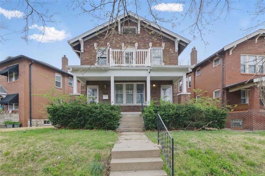 view of front of property featuring a balcony, a front yard, covered porch, and brick siding