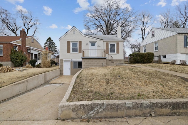 view of front facade with concrete driveway, a garage, and a chimney