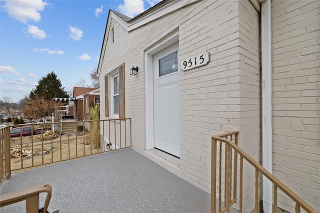 doorway to property featuring a balcony and brick siding