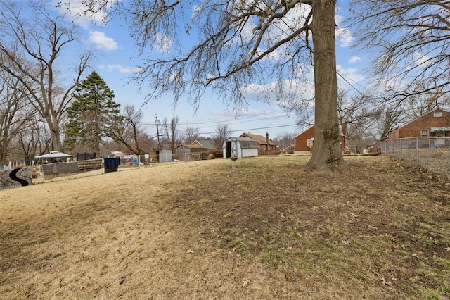 view of yard with fence, an outdoor structure, and a shed