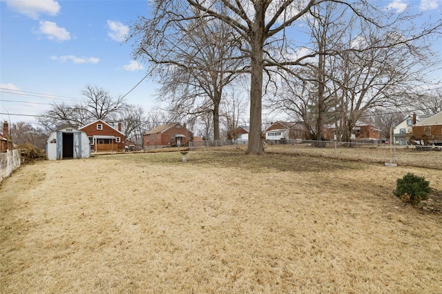 view of yard with an outbuilding, fence, and a storage shed