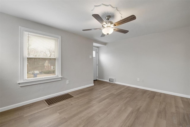 spare room featuring baseboards, visible vents, and wood finished floors