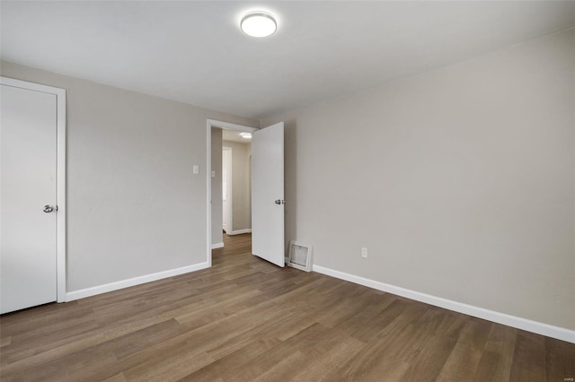 unfurnished room with wood finished floors, baseboards, and visible vents