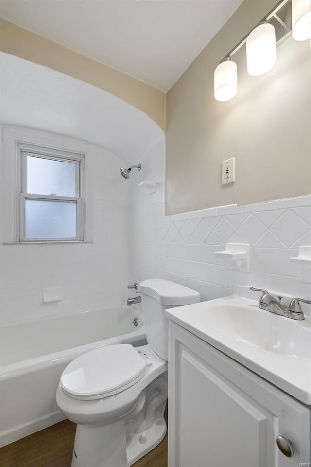 bathroom featuring a wainscoted wall, toilet, vanity, shower / bathing tub combination, and tile walls