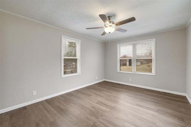 spare room featuring baseboards, ceiling fan, wood finished floors, and plenty of natural light
