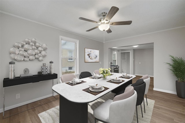 dining room with baseboards, wood finished floors, ornamental molding, and a ceiling fan