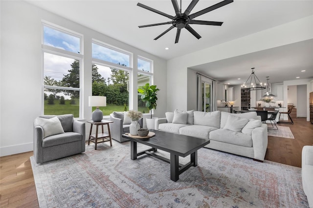 living room featuring baseboards, recessed lighting, wood finished floors, and ceiling fan with notable chandelier
