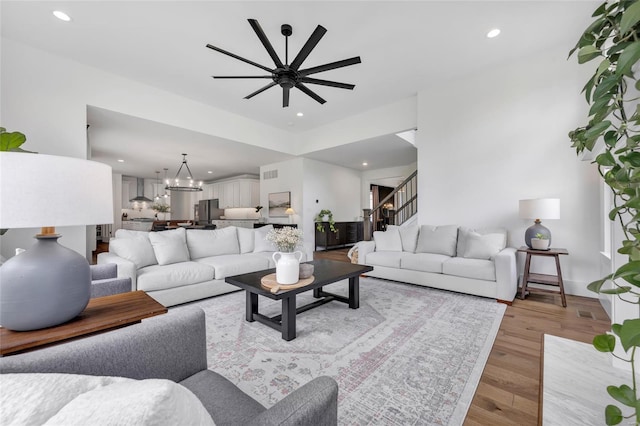 living room featuring light wood-type flooring, recessed lighting, and ceiling fan with notable chandelier