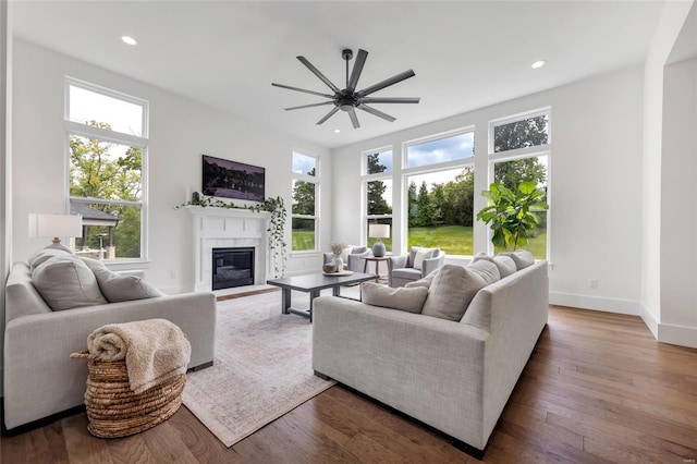 living room with a glass covered fireplace, recessed lighting, a ceiling fan, and wood finished floors