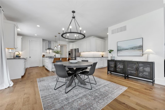 dining space with visible vents, light wood-style flooring, recessed lighting, and a notable chandelier
