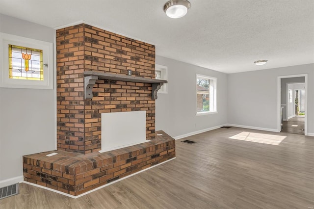 unfurnished living room with visible vents, baseboards, and wood finished floors