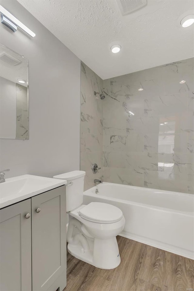 bathroom with visible vents, toilet, shower / bath combination, and wood finished floors