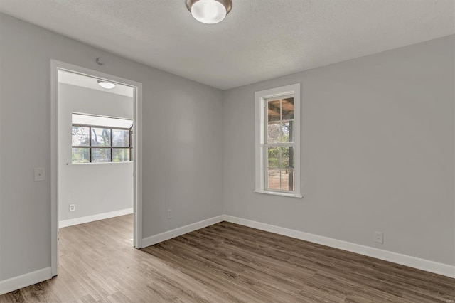 empty room featuring baseboards, a textured ceiling, and wood finished floors
