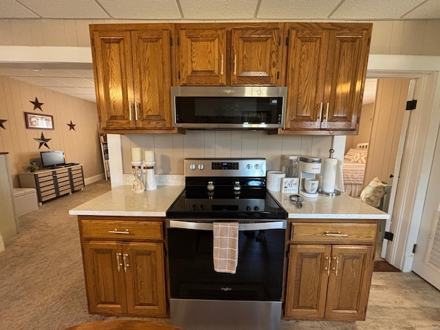 kitchen with light countertops, stainless steel appliances, tasteful backsplash, and brown cabinets