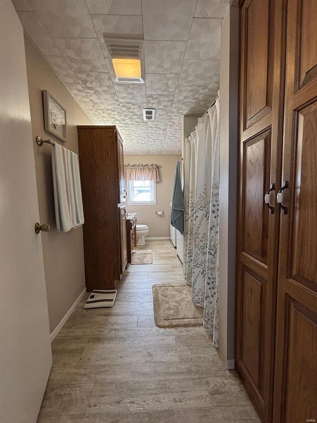 full bath featuring a shower with curtain, toilet, baseboards, visible vents, and wood finished floors