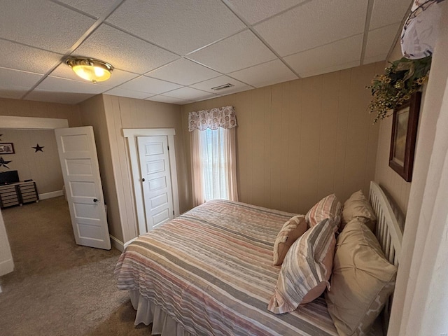 carpeted bedroom with visible vents and a drop ceiling