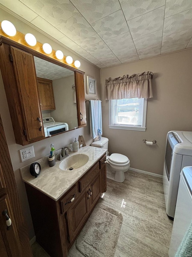 bathroom featuring toilet, vanity, baseboards, and washer and dryer