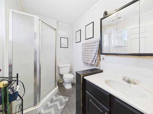 bathroom with toilet, vanity, crown molding, and a shower stall