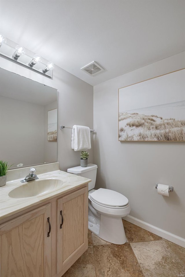 half bath with stone finish floor, visible vents, vanity, baseboards, and toilet