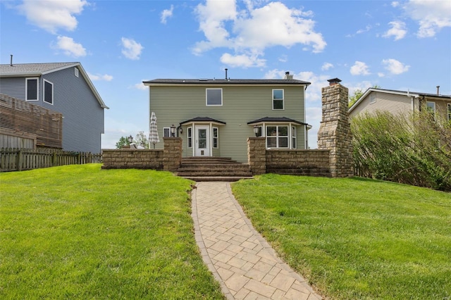 rear view of house with a yard, fence, and a chimney