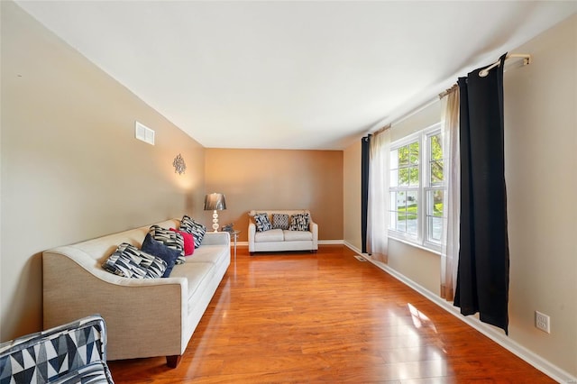living area featuring baseboards, visible vents, and light wood finished floors