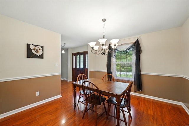 dining area featuring baseboards, wood finished floors, and a notable chandelier
