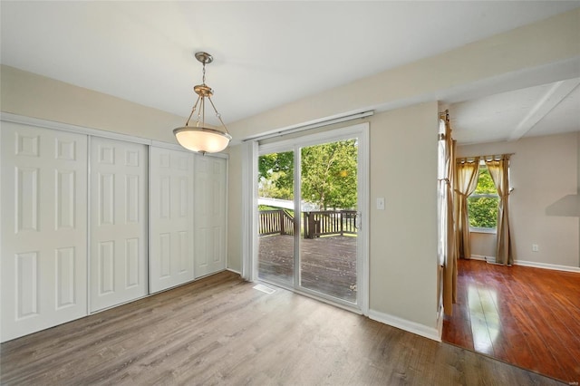 unfurnished dining area with baseboards, plenty of natural light, wood finished floors, and visible vents