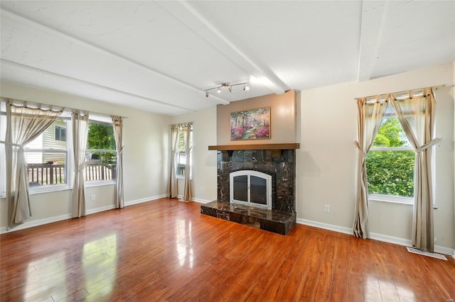 unfurnished living room with beam ceiling, a fireplace, baseboards, wood finished floors, and visible vents