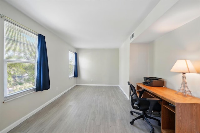 office with a healthy amount of sunlight, baseboards, wood finished floors, and visible vents
