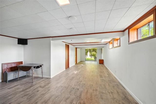 corridor with baseboards, ornamental molding, and wood finished floors