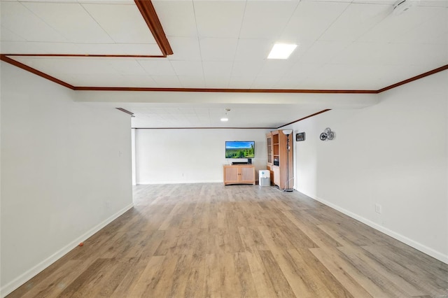 unfurnished living room featuring crown molding, light wood finished floors, and baseboards