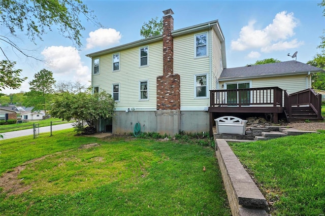 back of house with a lawn, a wooden deck, a chimney, and fence