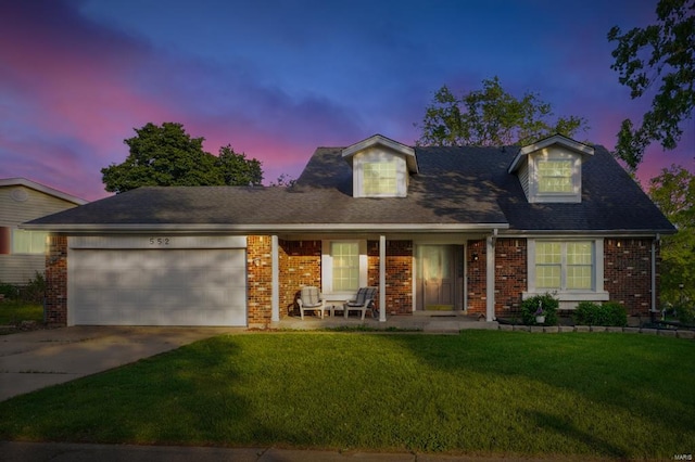 cape cod home with a garage, concrete driveway, brick siding, and a front yard