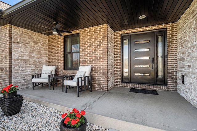 entrance to property featuring brick siding, a ceiling fan, and covered porch