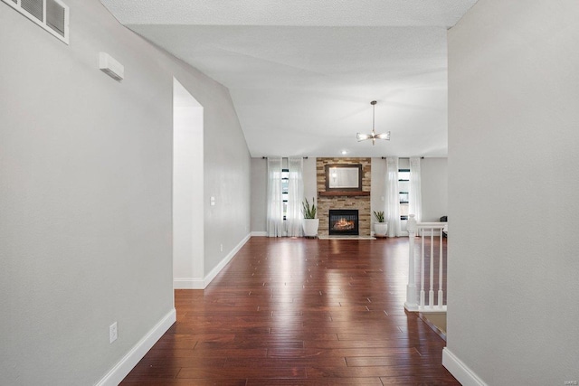 unfurnished living room featuring visible vents, baseboards, an inviting chandelier, and hardwood / wood-style flooring