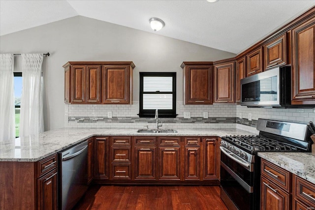 kitchen with dark wood-style floors, backsplash, lofted ceiling, stainless steel appliances, and a sink