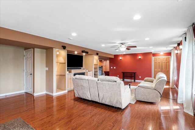 living room with a fireplace, wood finished floors, and ceiling fan