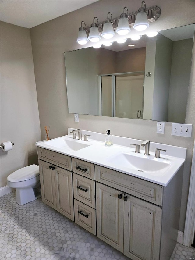 full bathroom featuring a shower stall, double vanity, a sink, and toilet