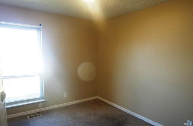 carpeted spare room with visible vents, baseboards, and a textured ceiling
