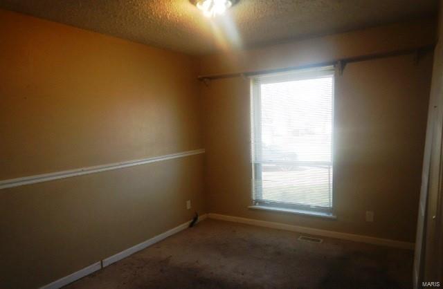 carpeted empty room with visible vents, baseboards, and a textured ceiling