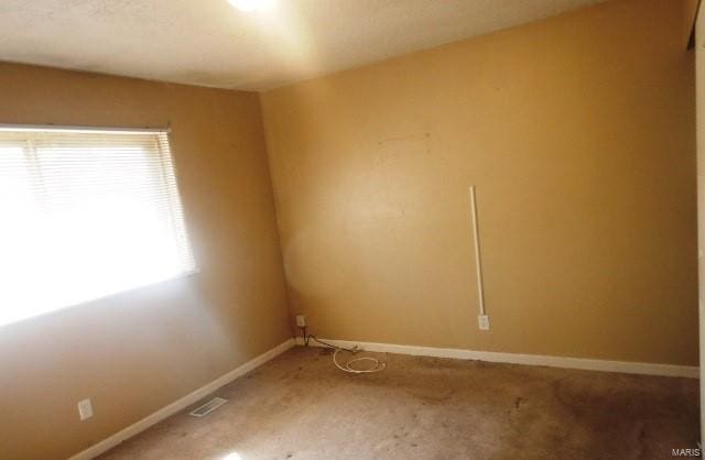 carpeted empty room with visible vents and baseboards