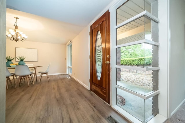 entrance foyer with a notable chandelier, baseboards, visible vents, and wood finished floors