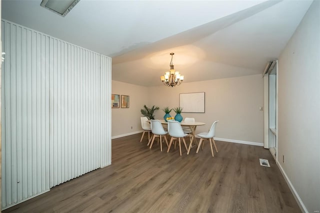 dining area with a notable chandelier, baseboards, visible vents, vaulted ceiling, and wood finished floors
