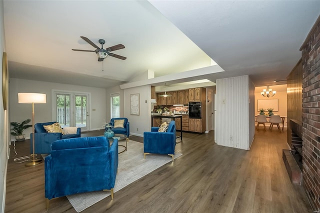 living room featuring dark wood-type flooring, baseboards, and ceiling fan with notable chandelier