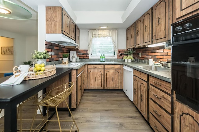 kitchen with a sink, black oven, backsplash, and white dishwasher